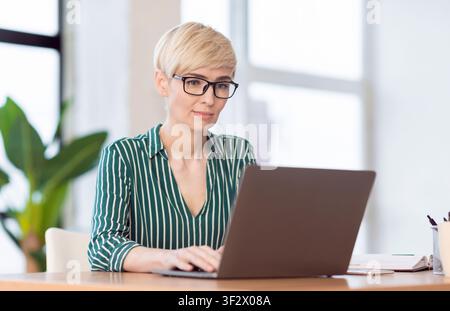 Office Manager Lady Working On Laptop Sitting At Workplace Indoor Stock Photo