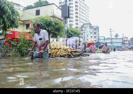 People past through a flooded street full of trash in the downtown of ...