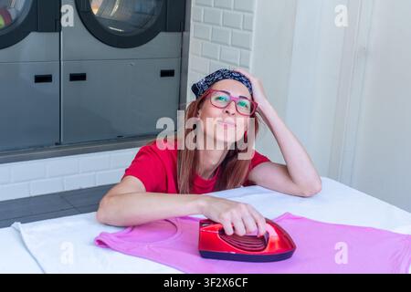 Woman ironing clothes in self service auto laundry Stock Photo