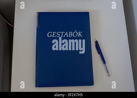 Blue guestbook with the Icelandic word Gestabók printed on the cover lying on a white nightstand next to a plastic pen Stock Photo