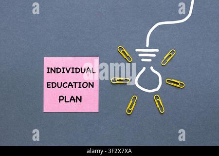 An individual education plan written on a pink sticky note and a hand-drawn light bulb. Business concept, IEP 504 Program, space for text. Gray backgr Stock Photo