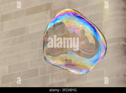 Iridescent soap bubble floating against a soft neutral background Stock Photo