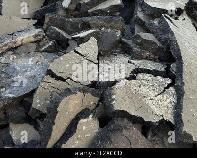 Cracked asphalt surface with irregular shapes in a close-up view, ideal for texture background. Mobile photo Stock Photo