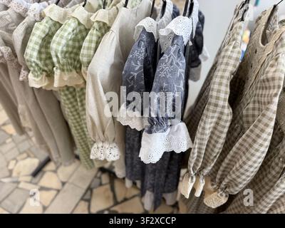 Vintage dresses on hangers in a boutique with a rustic tile floor background. Mobile photo Stock Photo