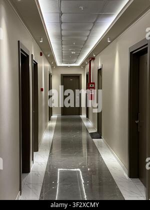 Hotel corridor featuring closed doors and shiny marble floor in a modern interior design. Mobile photo Stock Photo