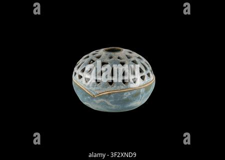 Round ceramic incense burner bowl with triangular cutouts and a textured glaze, photographed isolated on black; ideal for meditation, aromatherapy, ri Stock Photo