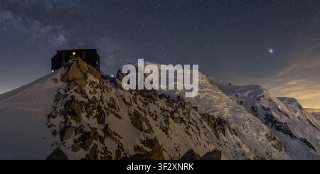 The Cosmiques Refuge (3613m) in the Mont-Blanc massif stands out against the backdrop of the Milky Way. To its right is Mont-Blanc du Tacul (4248m), w Stock Photo