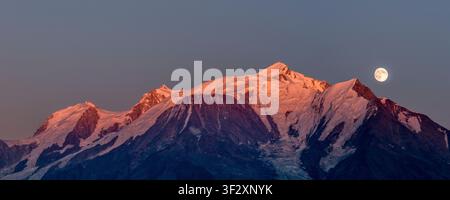Almost full moon rising behind Mont Blanc, while the setting sun still casts a pink glow on the 4000-meter peaks surrounding the roof of Europe, Cordo Stock Photo
