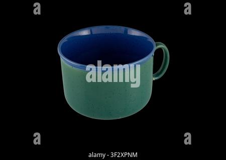 Green and blue speckled ceramic mug with a single handle photographed against a black background; a simple stoneware coffee cup ideal for product list Stock Photo