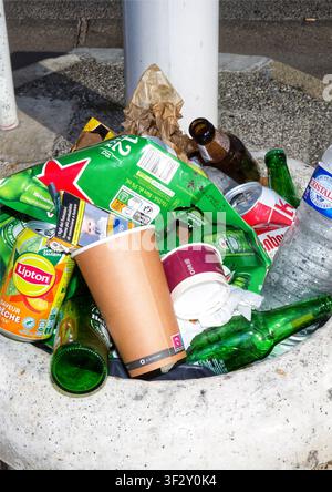 Overflowing public trash bin filled with discarded bottles, cans, takeaway cups and food packaging Stock Photo