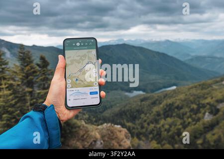 22 May 2026, Biogradska Gora, Montenegro: Hiker navigating mountainous terrain using a smartphone with a mapping application, tracking progress on a r Stock Photo