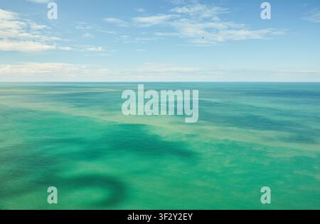 Aerial view of turquoise sea surface with dark underwater currents under blue sky in Etretat Normandy. Stock Photo