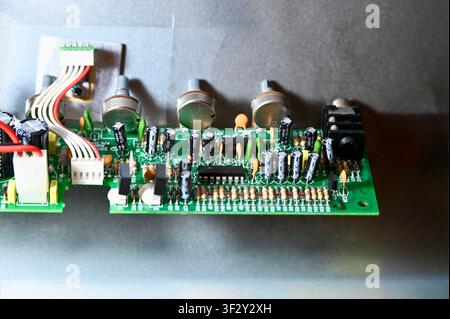 Close-Up of Printed Circuit Board with Capacitors, Resistors, and Potentiometers. High quality photoDetailed macro shot of a green printed circuit board (PCB) showing electronic components including electrolytic capacitors, resistors, potentiometers, microchips, and wiring. Ideal for concepts of hardware engineering, electronics repair, audio equipment manufacturing, and technology design. Stock Photo