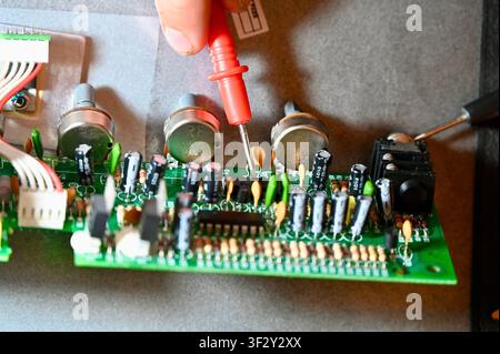 Close-Up of Printed Circuit Board with Capacitors, Resistors, and Potentiometers. High quality photoDetailed macro shot of a green printed circuit board (PCB) showing electronic components including electrolytic capacitors, resistors, potentiometers, microchips, and wiring. Ideal for concepts of hardware engineering, electronics repair, audio equipment manufacturing, and technology design. Stock Photo