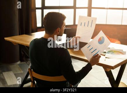 Young Manager Looking Through Documents Working In Office, Back View Stock Photo