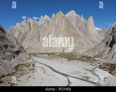 Aerial view of the rugged Karakoram mountain range with sharp peaks, a winding river flowing through a dry valley, and sparse vegetation in Khaplu, Pa Stock Photo