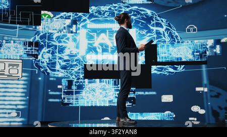 Tech savvy administrator reviewing AI brain programming on a tablet, exploring algorithmic thinking and deep learning through neural networks system. Artificial intelligence coding. Camera B. Stock Photo