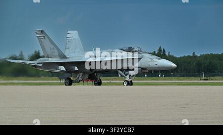 Royal Canadian Air Force CF-18 Hornet fighter jet taxis on a concrete runway at an airbase, showing cockpit, landing gear and gray camouflage details. Stock Photo