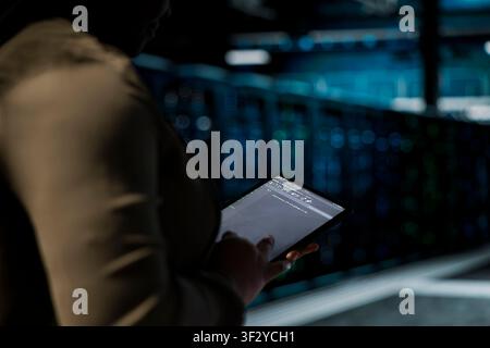 Close up of system administrator using tablet in sustainable data center, implementing green technologies. IT specialist working on energy efficient solutions to reduce server room carbon footprint Stock Photo