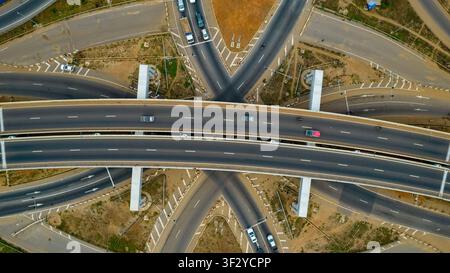 Aerial view of the Tema Motorway interchange featuring multi-level flyovers and connecting roads with vehicles moving through the junction in Accra, G Stock Photo