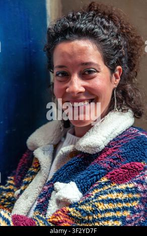 Smiling woman with curly hair wearing colorful patterned jacket Stock Photo