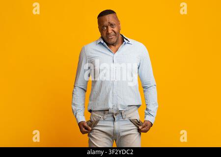 Sad mature african american man showing empty pockets Stock Photo