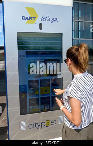 DALLAS, TX, USA - JULY 11, 2026: A woman interacts with a DART digital information kiosk at a transit station in Dallas. The kiosk provides transit up Stock Photo