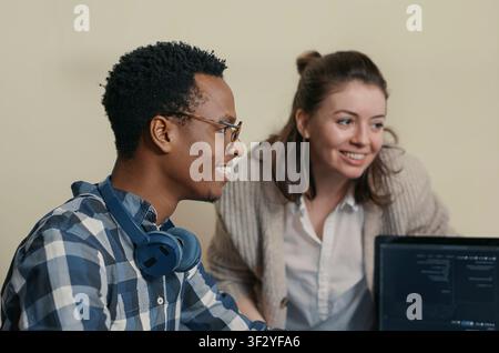 System engineers celebrate successful code compilation with a high five, congratulating a coworker while analyzing algorithms on multiple computer screens. Stock Photo