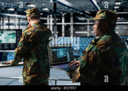 Soldier monitoring AI assisted defense systems in military data command center. Army expert overseeing real time analytics powered by artificial intelligence in army operations hub Stock Photo