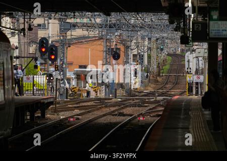 Yamato-Saidaiji Station in Nara, Japan is pictured as commuters await trains on the platform. The station features multiple tracks and overhead electr Stock Photo