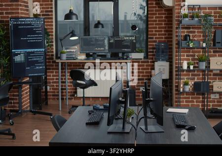 Empty software IT agency office and computers in background with multiple monitors, programming code and cloud computing visuals inside an empty software agency workspace. Stock Photo