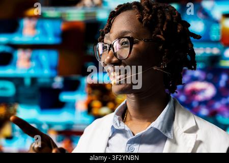 Closeup of happy woman doing key note presentation using holographic medical data chart. Cheerful biomedical expert using diagnostic software to present human organ scans diagrams to audience at event Stock Photo