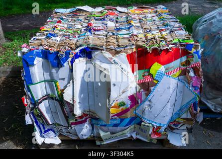 Close-up of a compressed bale of used cardboard packaging and corrugated boxes produced by a cardboard baler behind a supermarket in Germany. Stock Photo
