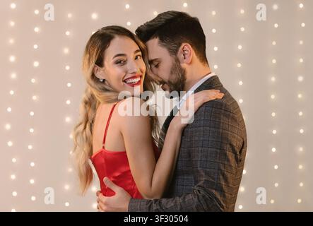 Attractive couple embracing and bonding while standing over beige background indoors Stock Photo