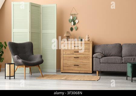 Modern living room interior with a gray armchair, wooden dresser, and a mint green room divider Stock Photo