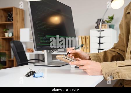 Female programmers hands writing in notebook at office Stock Photo