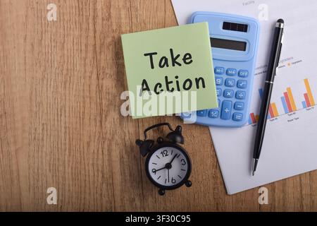 Take action concept with sticky note, calculator, alarm clock, and financial report on desk, symbolizing productivity, decision making, business plann Stock Photo