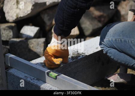 Construction worker uses level tool outdoors on a project Stock Photo