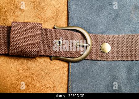 Close-up shot of a brown textile belt strap with a brass buckle, showing intricate textures of suede and canvas from a vintage bag or garment accessor Stock Photo