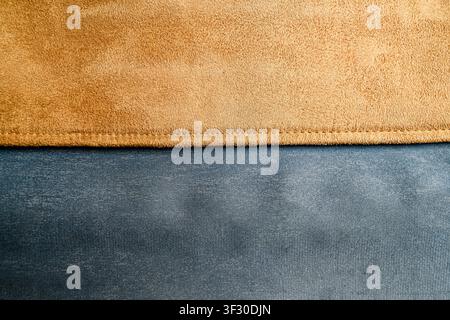A close-up view of a blue denim and brown suede fabric background joined by a horizontal stitched seam. Perfect for textile and fashion design concept Stock Photo