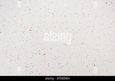 Close-up of a white surface featuring a fine pattern of reddish-brown paint splatters and spots, creating a clean abstract texture for design backgrou Stock Photo