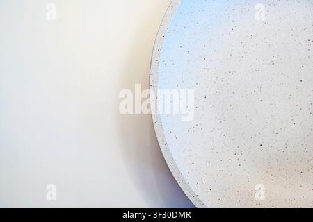 A top-down view of a modern white ceramic bowl with brown speckles, set against a clean off-white background. Perfect for minimalist food photography Stock Photo
