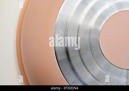 A detailed macro shot showing the bottom of a peach-colored frying pan with silver concentric circles designed for even heat distribution. Minimalist Stock Photo