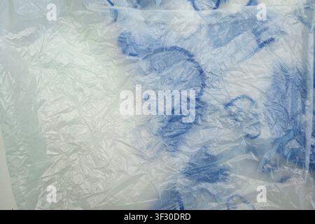 High-resolution close-up of a crumpled white translucent plastic bag with blue printing, showing detailed wrinkles, folds, and texture for background Stock Photo