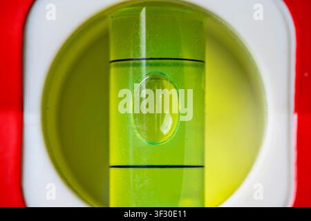 A macro view of a green spirit level vial. The air bubble is perfectly centered between the black marks, indicating a level surface for construction a Stock Photo
