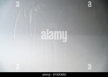 A close-up view of a gray painted surface featuring vertical liquid streaks and drips, creating a grunge industrial background for design projects Stock Photo