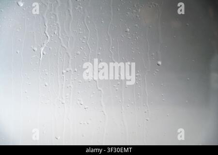 A close-up view of a gray painted surface featuring vertical liquid streaks and drips, creating a grunge industrial background for design projects Stock Photo