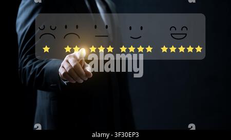 Professional businessman interacting with a digital interface for customer feedback. Virtual display showing star icons and facial expressions to eval Stock Photo