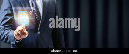 A businessman in a suit interacts with a glowing digital document icon, representing modern paperless office solutions, data management, and cloud sto Stock Photo