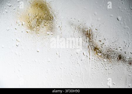 A close-up view of a gray painted surface featuring vertical liquid streaks and drips, creating a grunge industrial background for design projects Stock Photo